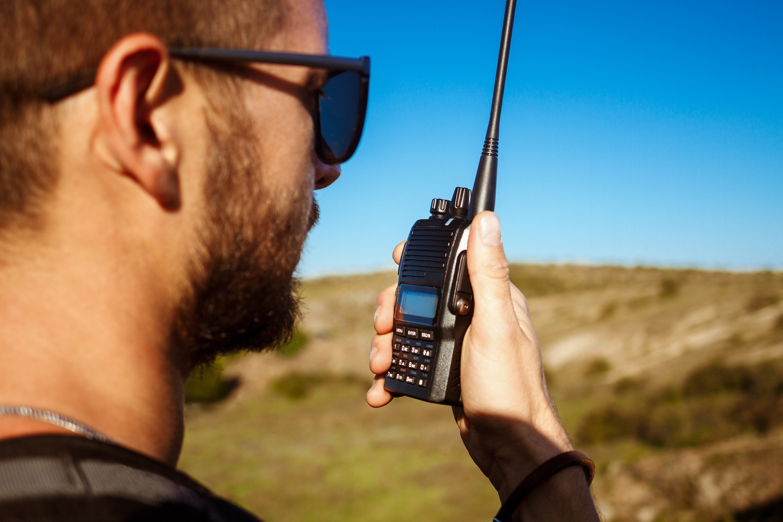 Radioaficionado operando un handie en terreno, con la antena apuntando al cielo